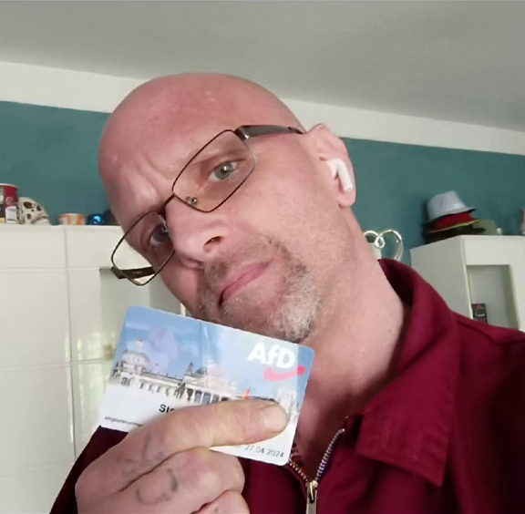Stephan M. hält eine AfD-Parteimitgliedskarte in der Hand.