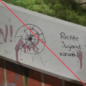 In schwarzem Marker gezeichnete Schwarze Sonne und rechts daneben der Schriftzug "Rechte Jugend voran!", an einem Betonteil eines Treppenaufganges.
