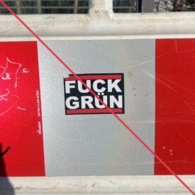 Aufkleber mit Aufschrift "Fuck Grün" auf einem Absperrzaun.