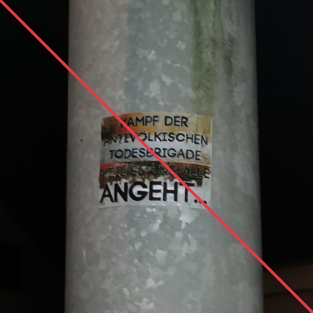 Aufkleber mit Aufschrift "Kampf der antivölkischen Todesbrigade / Weil es uns alle angeht" an einem Schildermast.