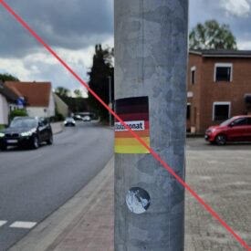 Aufkleber mit Aufschrift "#Stolzmonat" an einem Laternenmast.