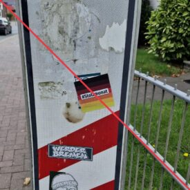 Aufkleber mit Aufschrift "#Stolzmonat" an einer Bahnübergangs-Bake.