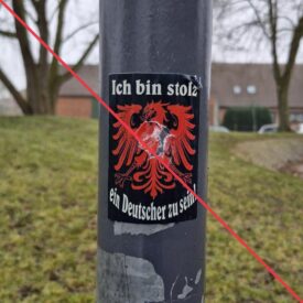 Aufkleber mit Aufschrift "Ich bin stolz ein Deutscher zu sein" auf einem Schildermast.